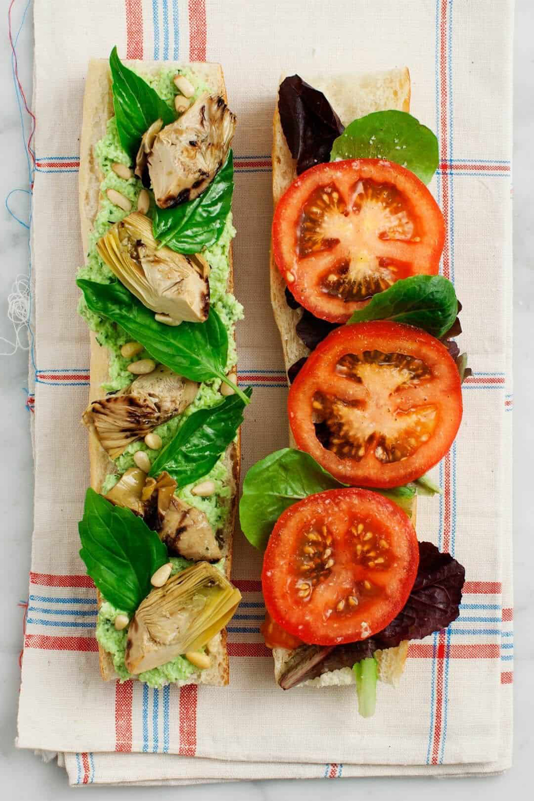 a baguette topped with basil, pesto and tomatoes