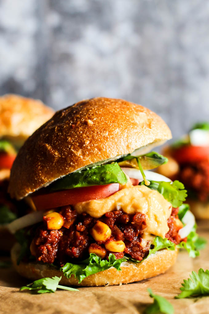 a vegan mini sloppy joe topped with cheese sauce, tomato, lettuce and onion