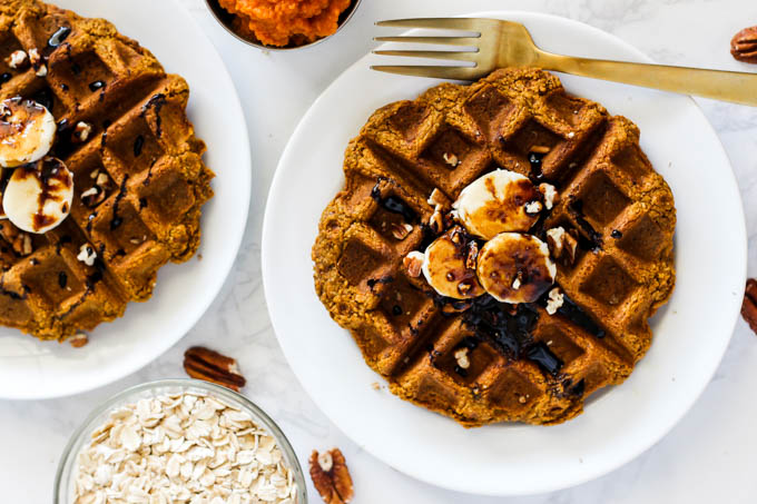 two pumpkin waffles topped with bananas, pecans and molasses