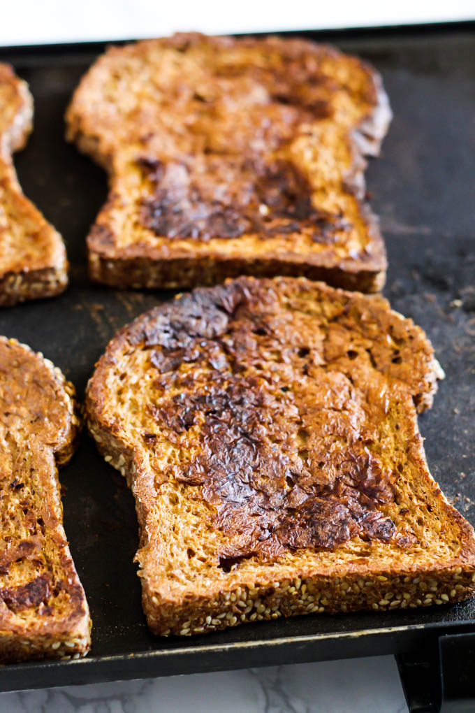 a griddle with four pieces of french toast being fried