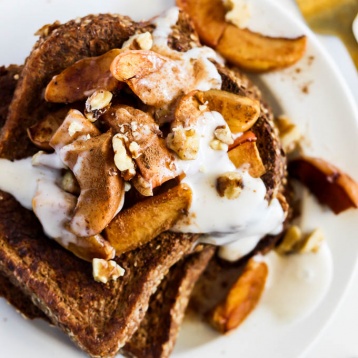 a plate of french toast topped with apples, walnuts and vegan yogurt