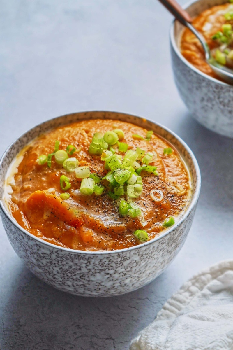 a bowl of sweet potato soup topped off with sliced scallions