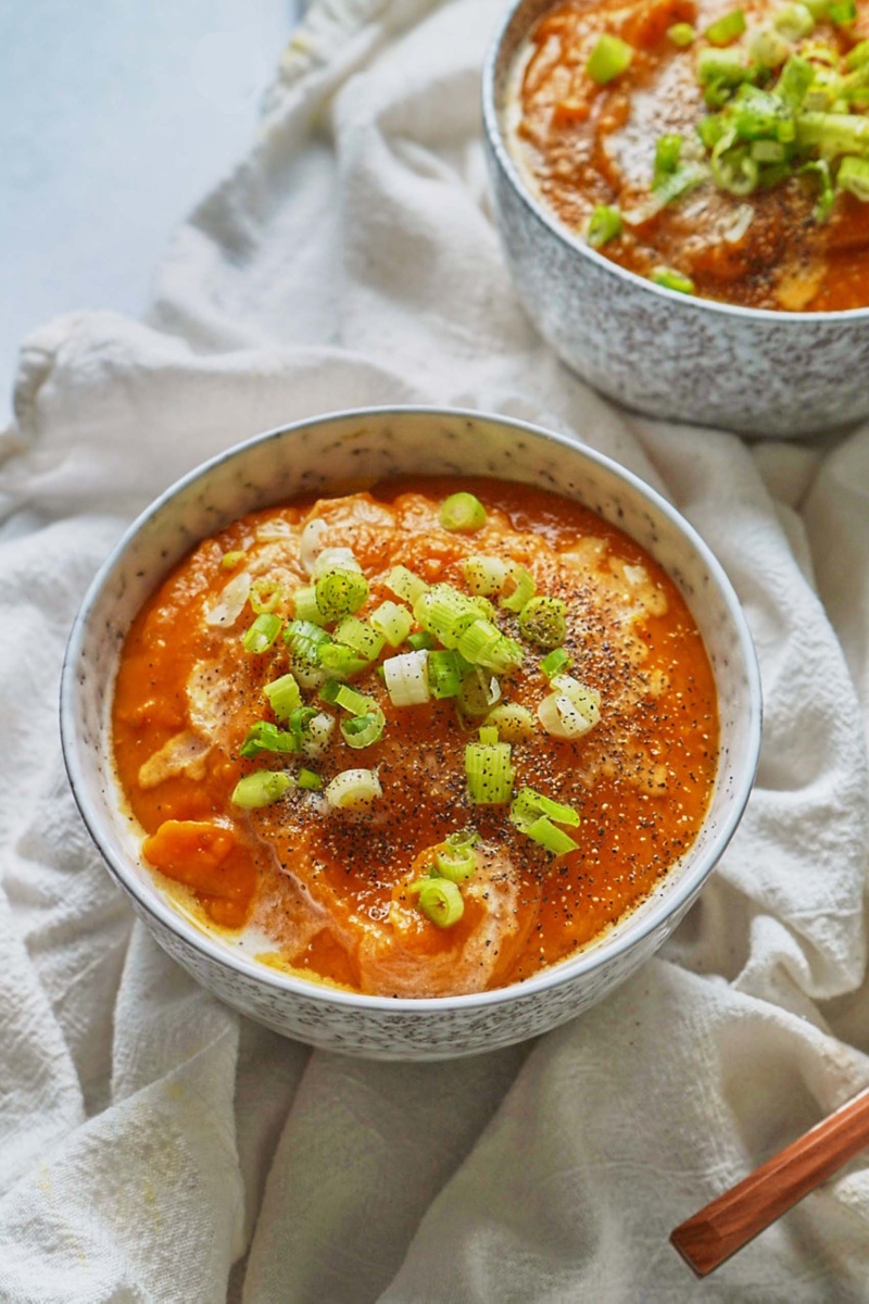 two bowls of sweet potato soup garnished with green onion