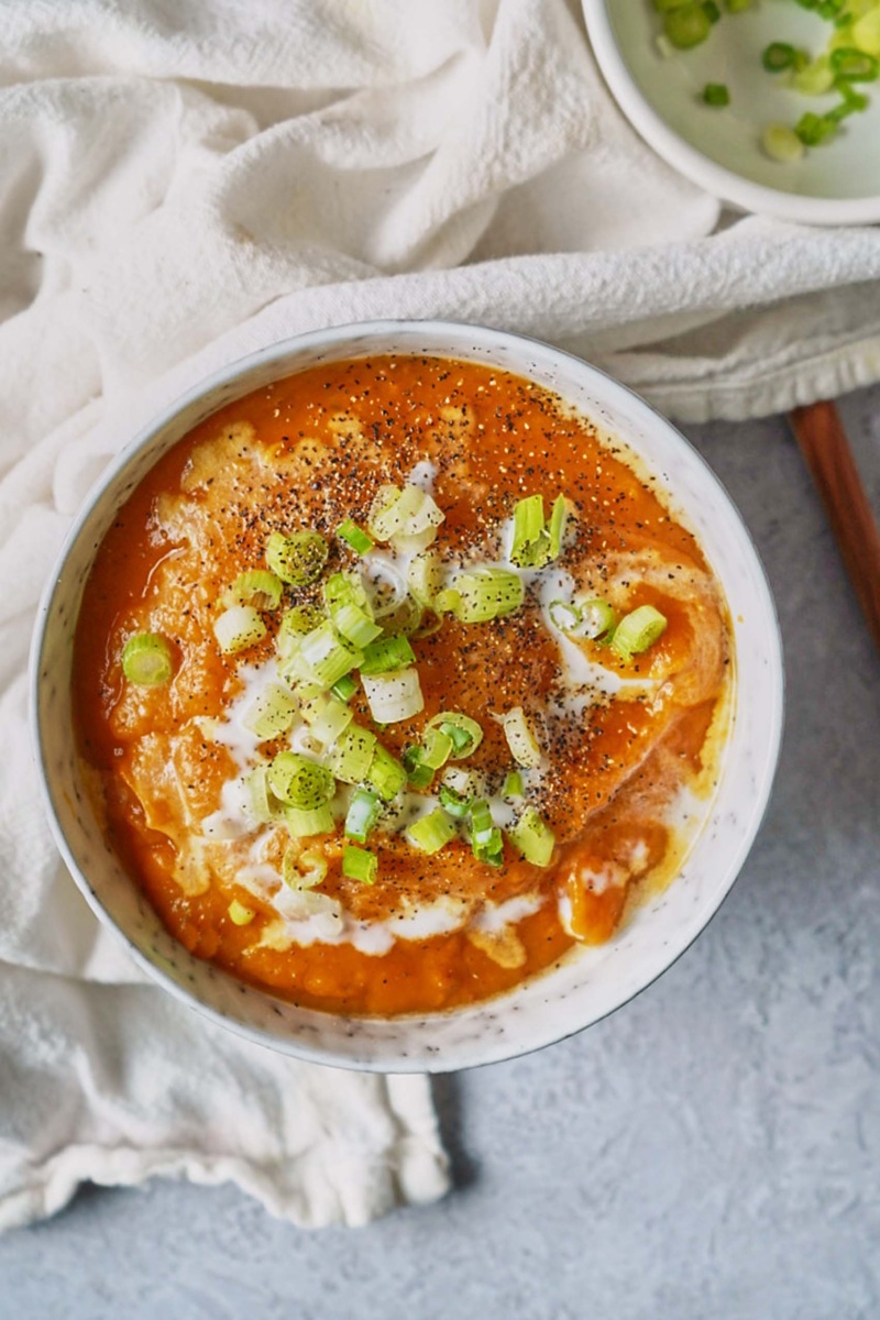 a bowl of sweet potato coconut soup topped with sliced green onion