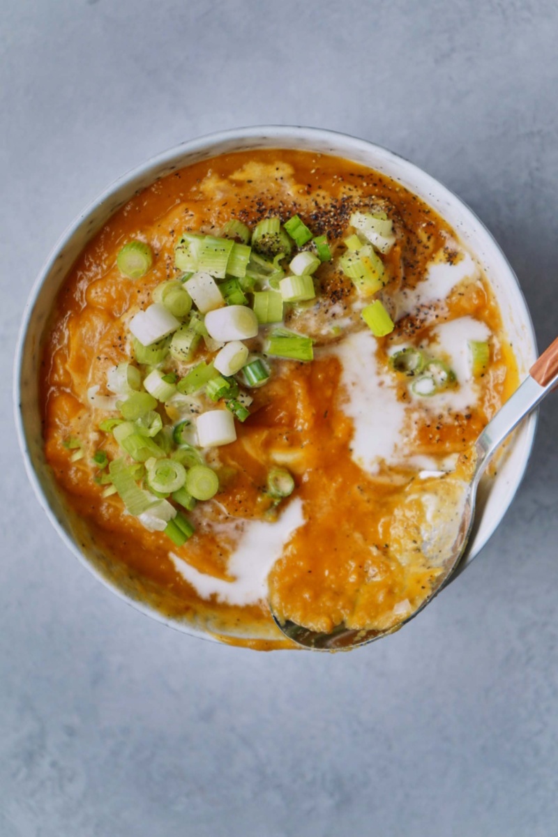 a spoon digging into a bowl of sweet potato soup