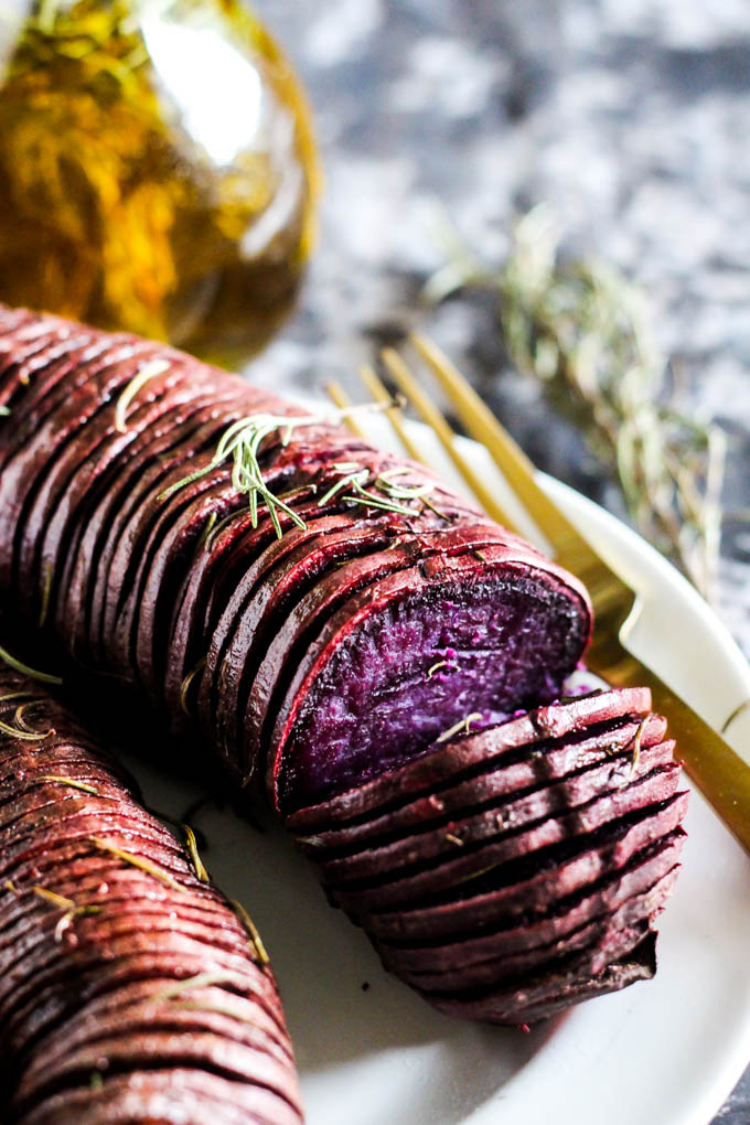 a hasselback style purple potato topped with rosemary