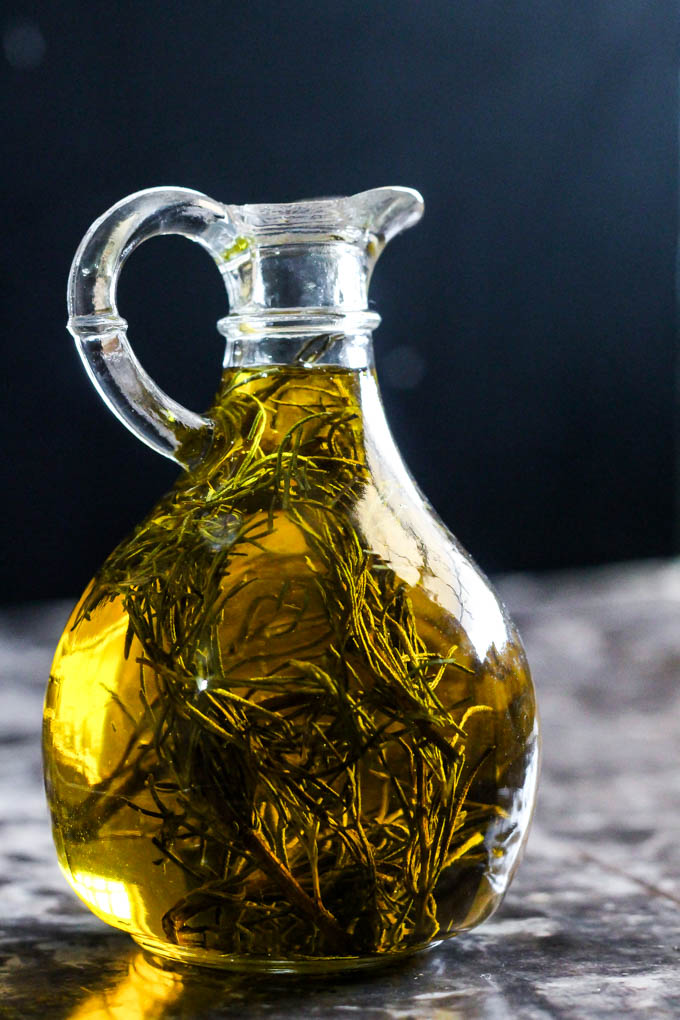 a glass jar of olive oil containing fresh rosemary