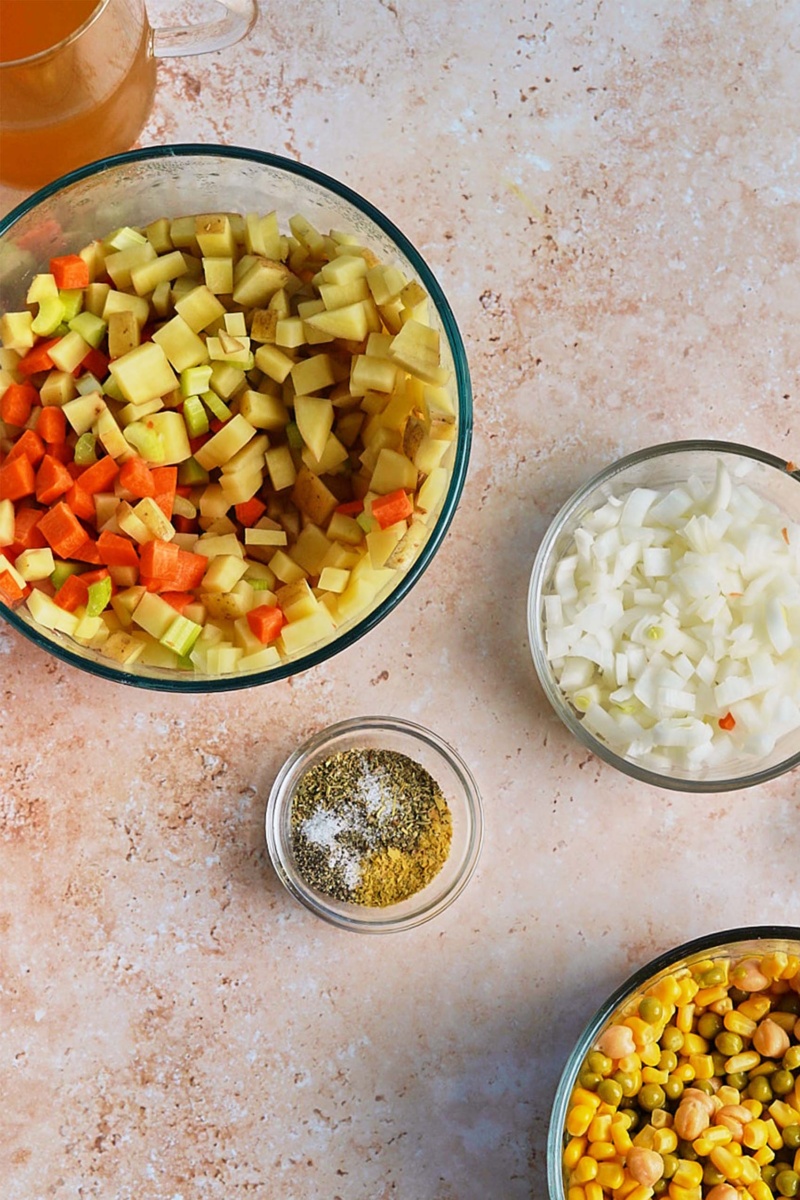 a bowl of diced veggies, a bowl of chopped onion, a bowl of seasonings and a bowl of chickpeas