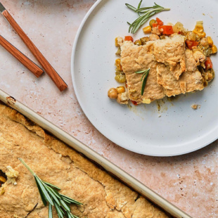 a casserole dish of vegan pot pie next to a single slice on a plate