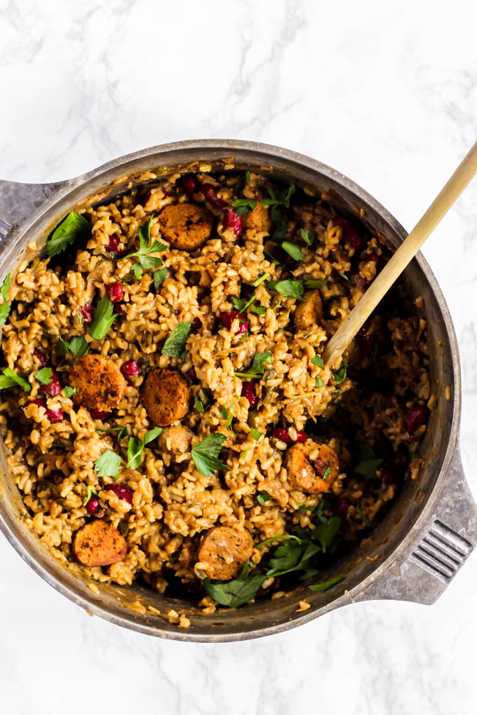 a pot of vegan jambalaya being stirred with a wooden spoon