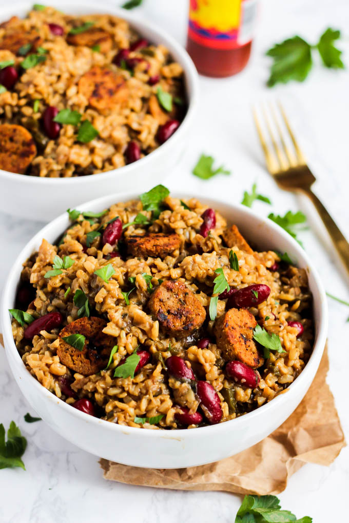 two bowls of jambalaya served with a bottle of hot sauce