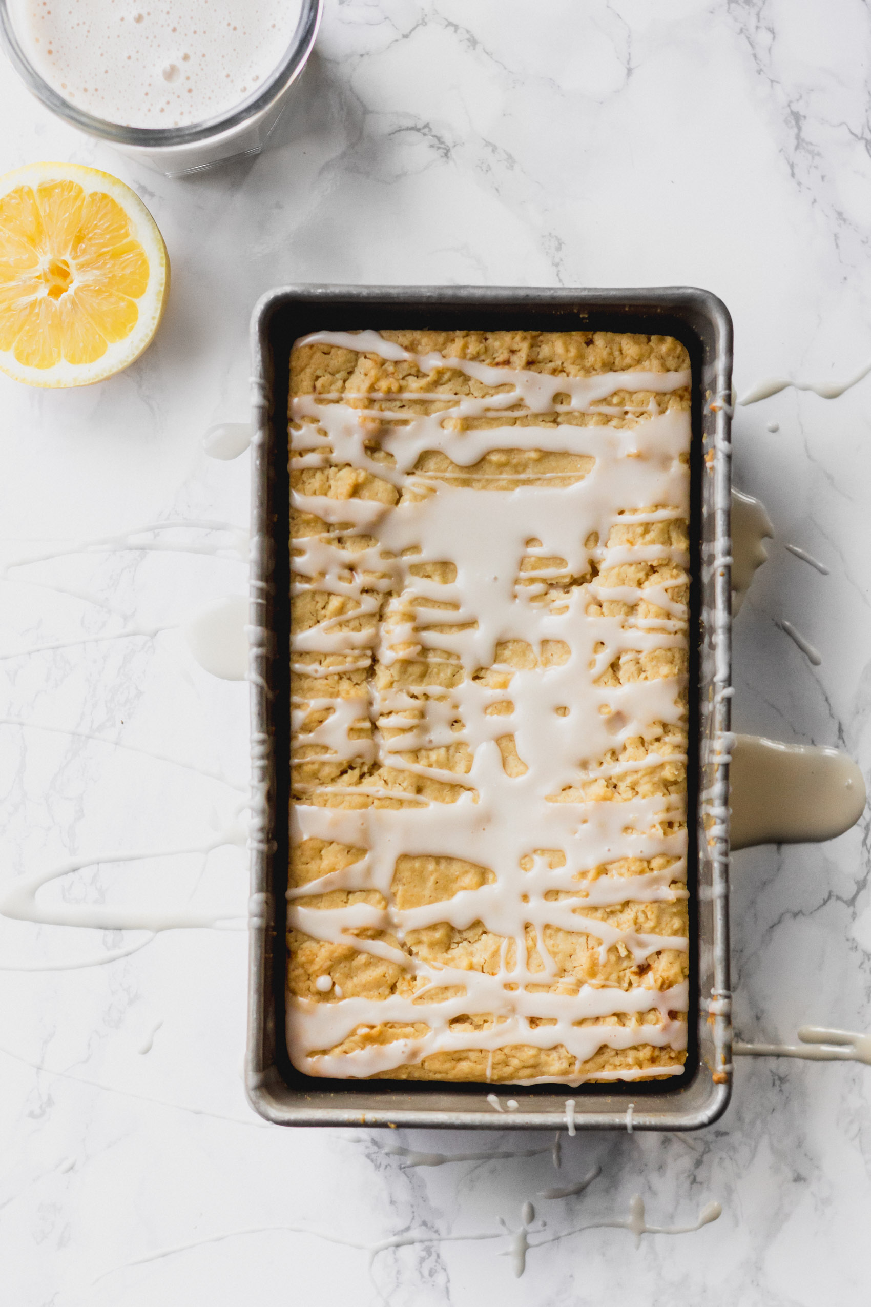 a loaf pan with a baked lemon bread topped with glaze