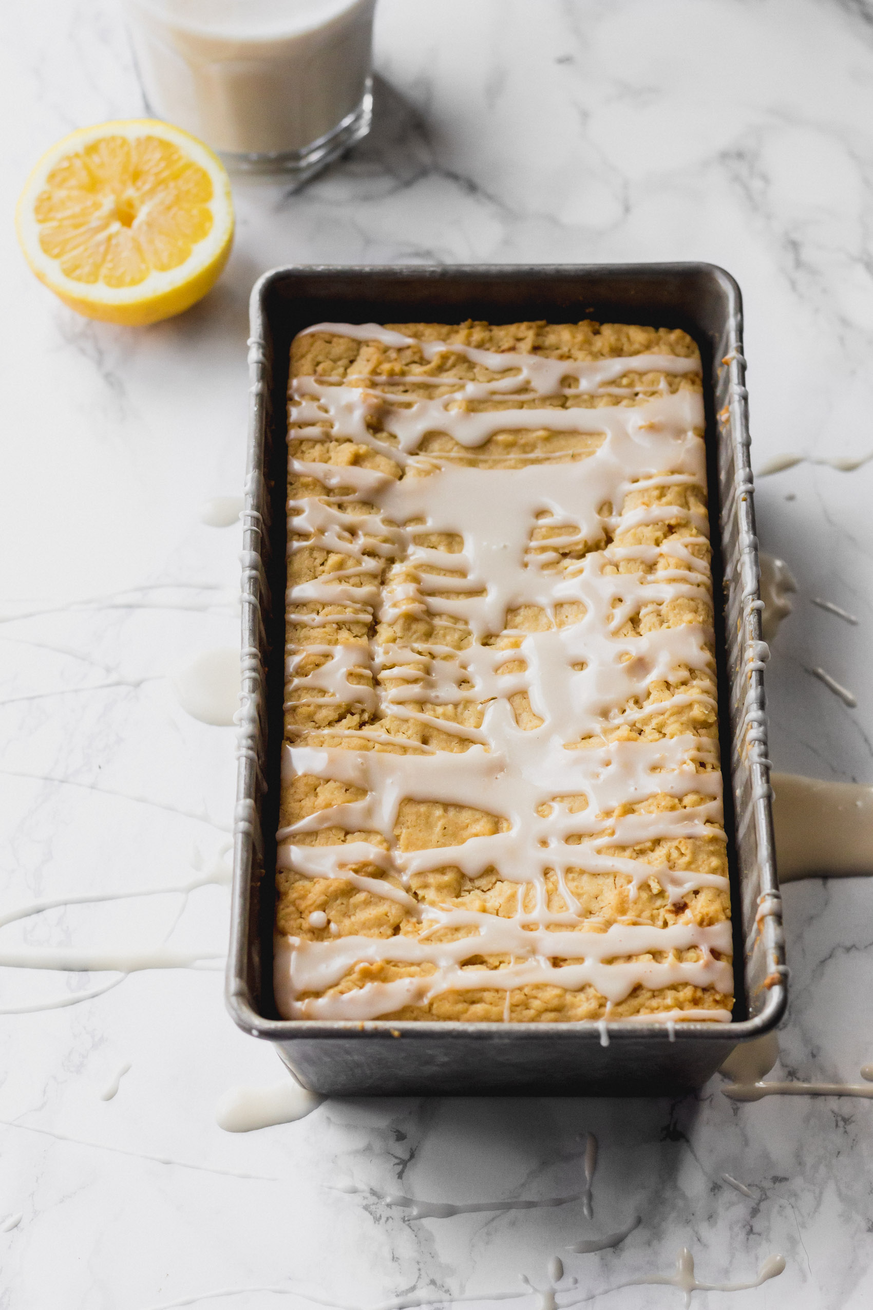 a vegan lemon loaf topped with a drizzle of glaze