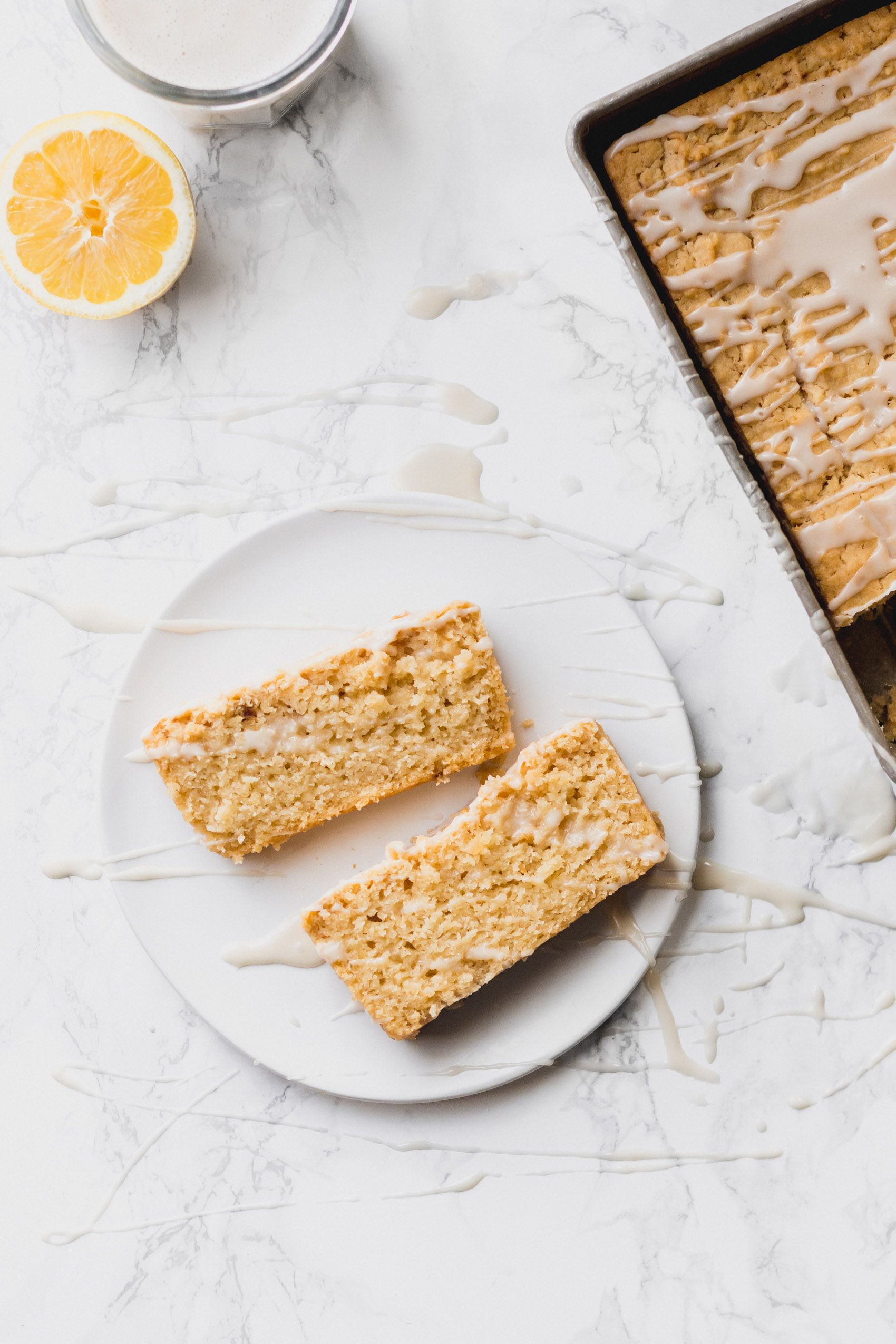 two sliced of lemon tea cake next to the full loaf in a baking dish