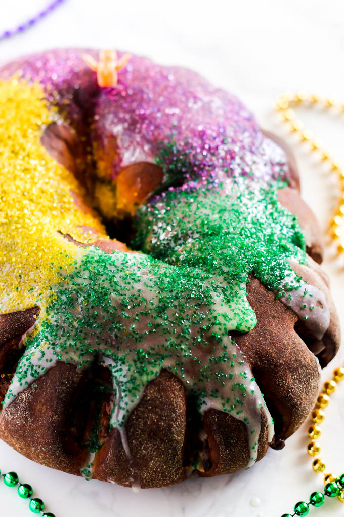 a frosted king cake featuring gold, green and purple sprinkles