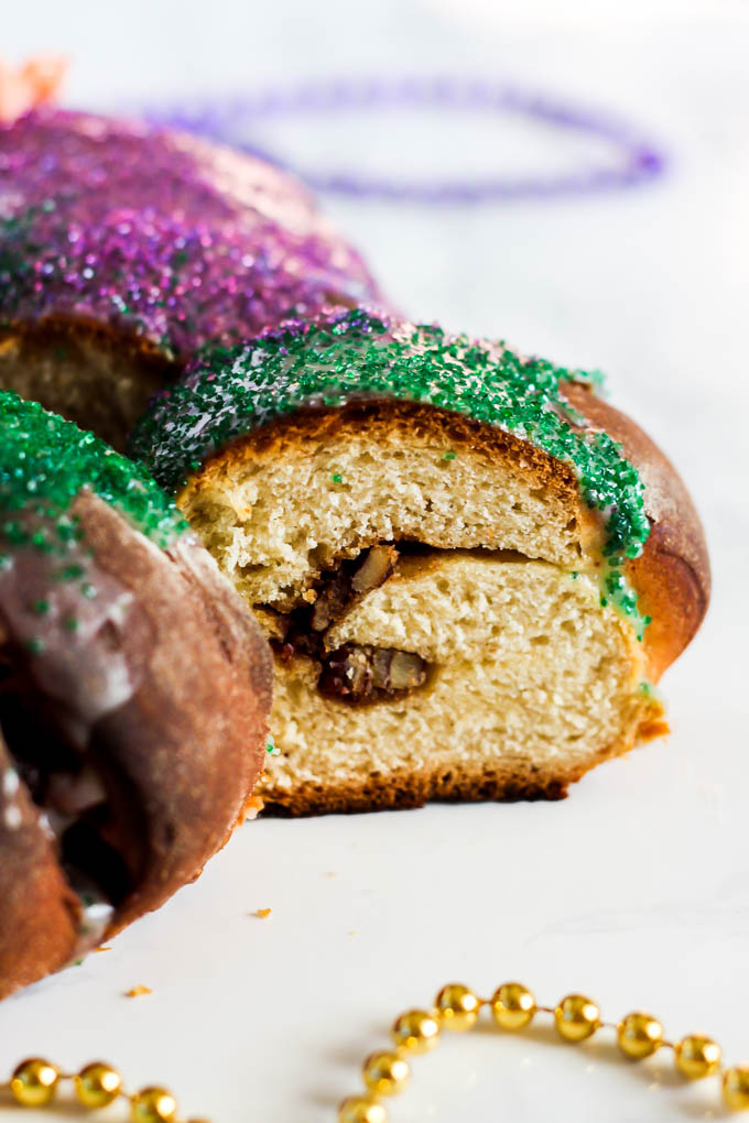 a slice of king cake being pulled from the larger cake