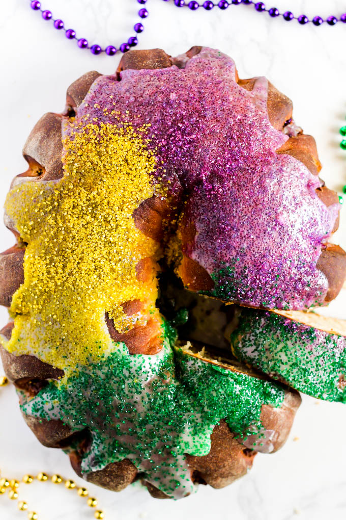 a mardi gras king cake with a slice being removed