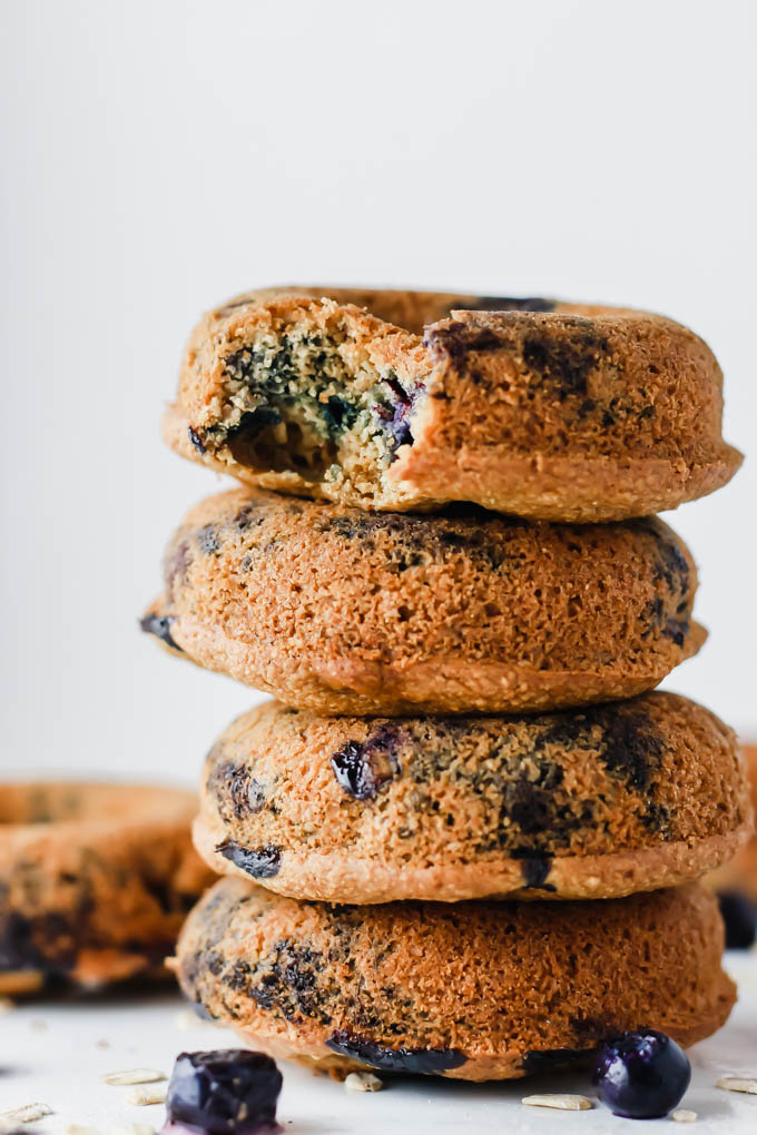 A stack of vegan blueberry donuts with a bite taken out of the top donut