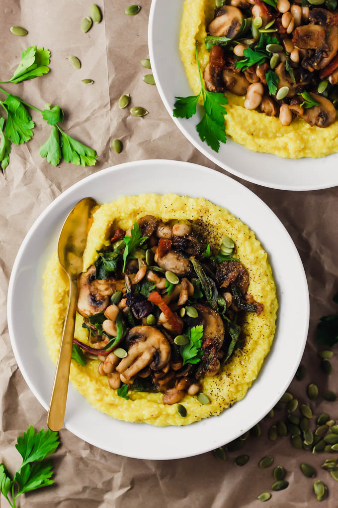 two bowls of polenta topped with vegetables and pumpkin seeds