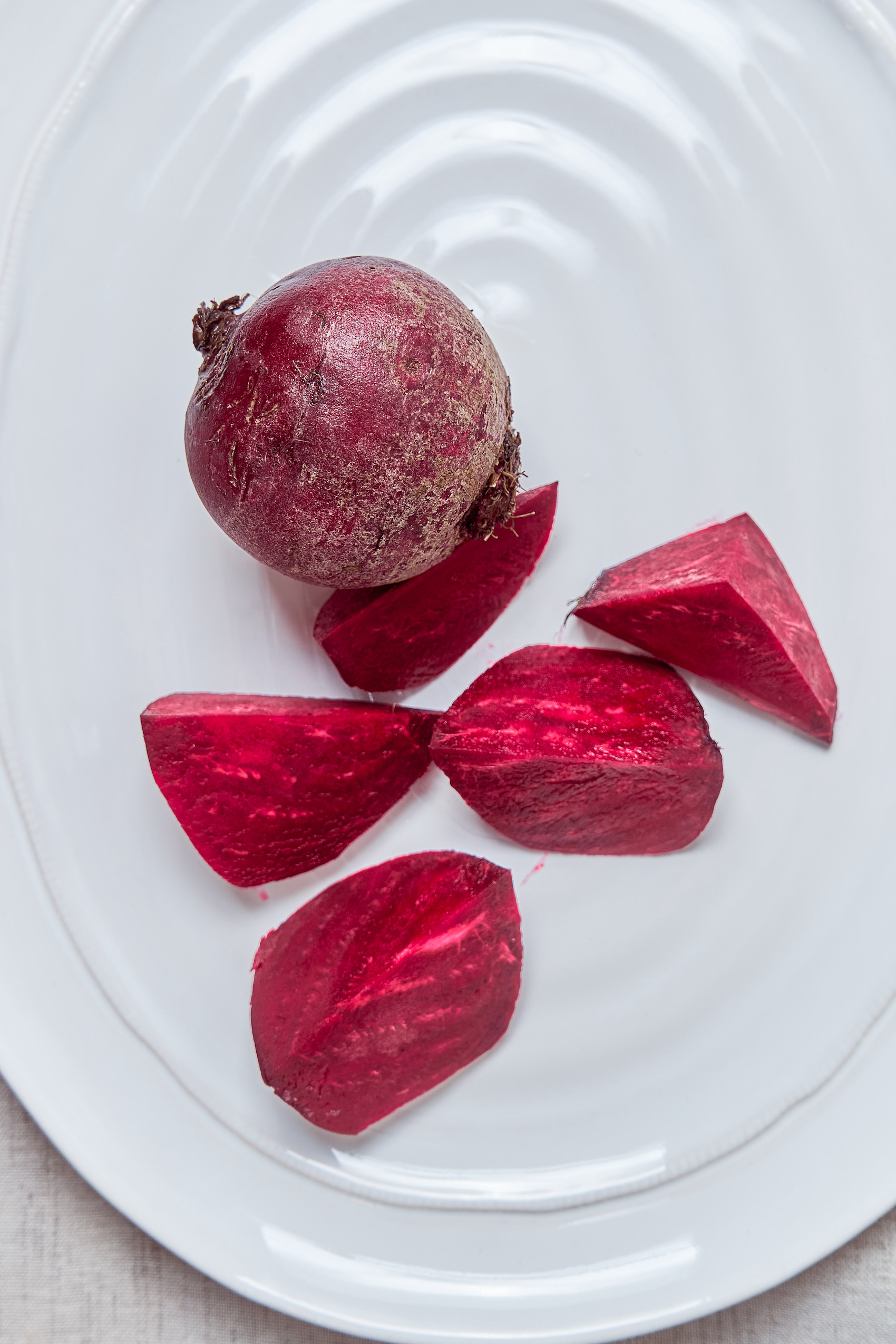 a plate with a full beet and a beet that has been cut into pieces