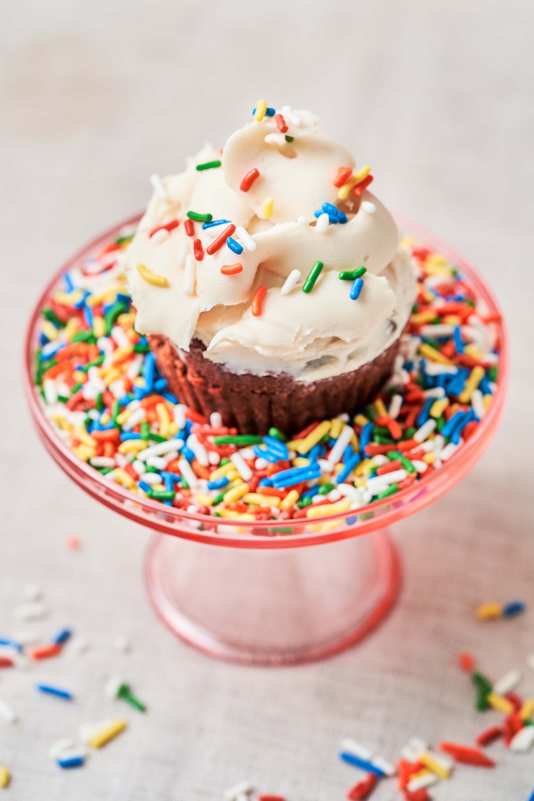 an overhead shot of a cupcake with vanilla frosting and sprinkles
