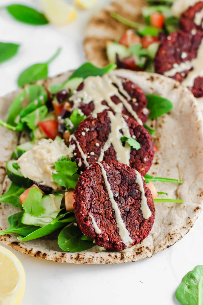 a whole wheat pita topped with greens and beet falafel patties