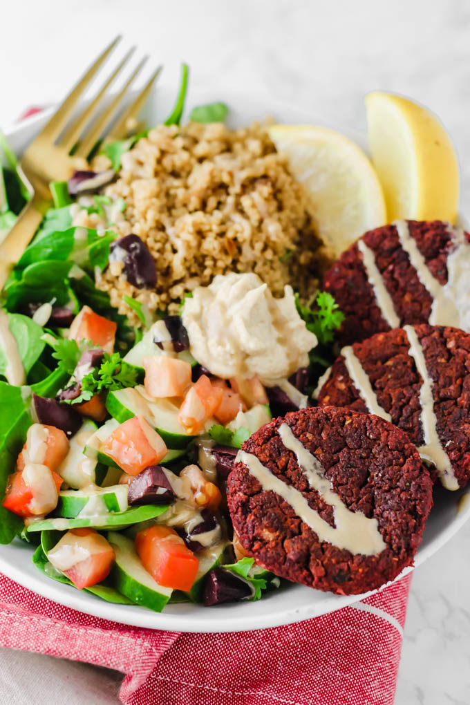 a bowl with greens, veggies, tahini, quinoa, hummus and falafel