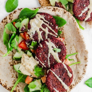 two pitas each topped with greens, tahini and falafel