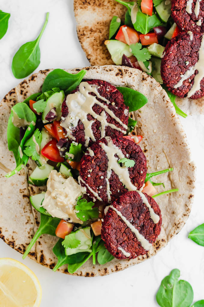 two pitas each topped with greens, tahini and falafel