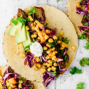 vegan corn tacos filled with veggie burgers avocado and sour cream