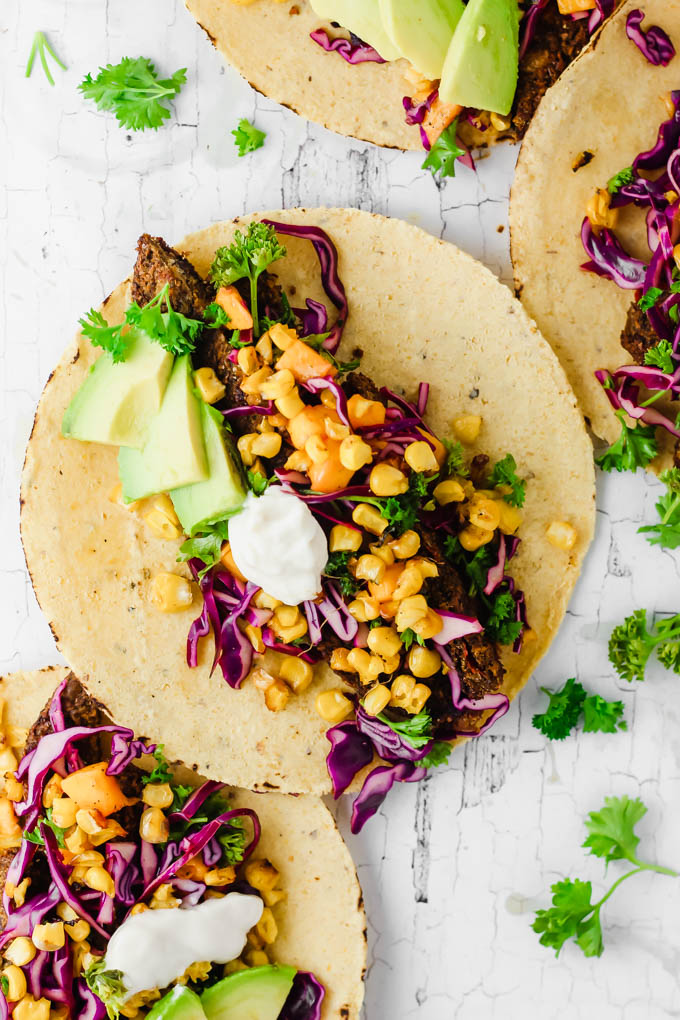 vegan corn tacos filled with veggie burgers avocado and sour cream