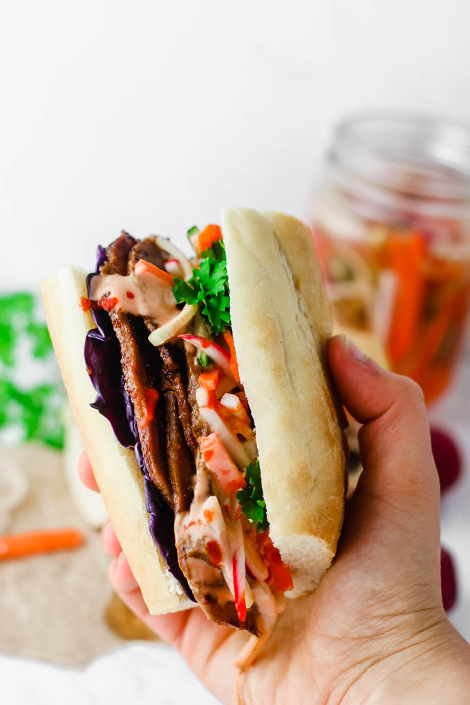 Layers of seitan are piled high with pickled vegetables and Sriracha mayo on a fluffy baguette in this Vegan Banh Mi! These satisfying sandwiches are great for packable lunches or to serve to a crowd.