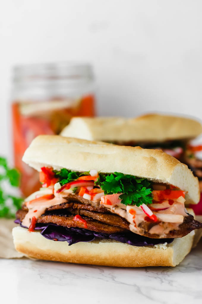 Layers of seitan are piled high with pickled vegetables and Sriracha mayo on a fluffy baguette in this Vegan Banh Mi! These satisfying sandwiches are great for packable lunches or to serve to a crowd.