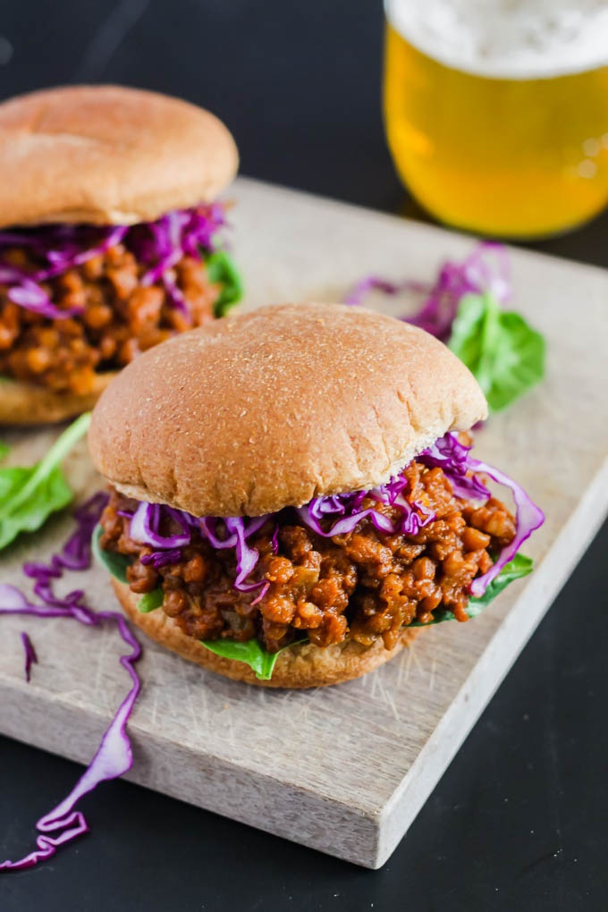 Two vegan bbq lentil sandwiches topped with cabbage and lettuce