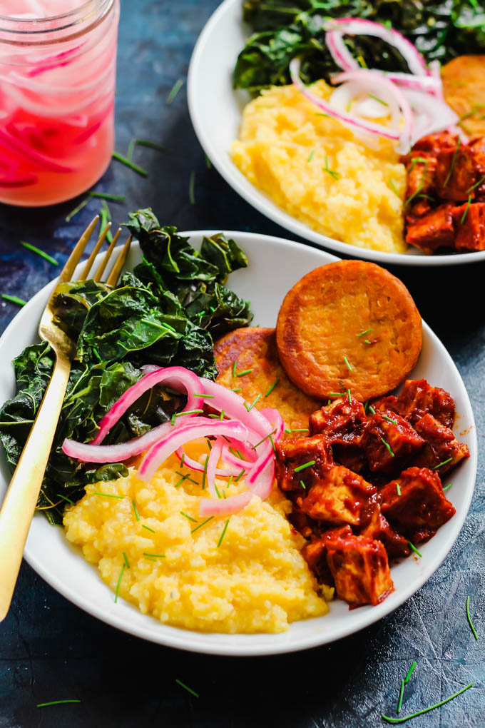 two bowls of grits with bbq tofu, collard greens and sweet potato hash browns