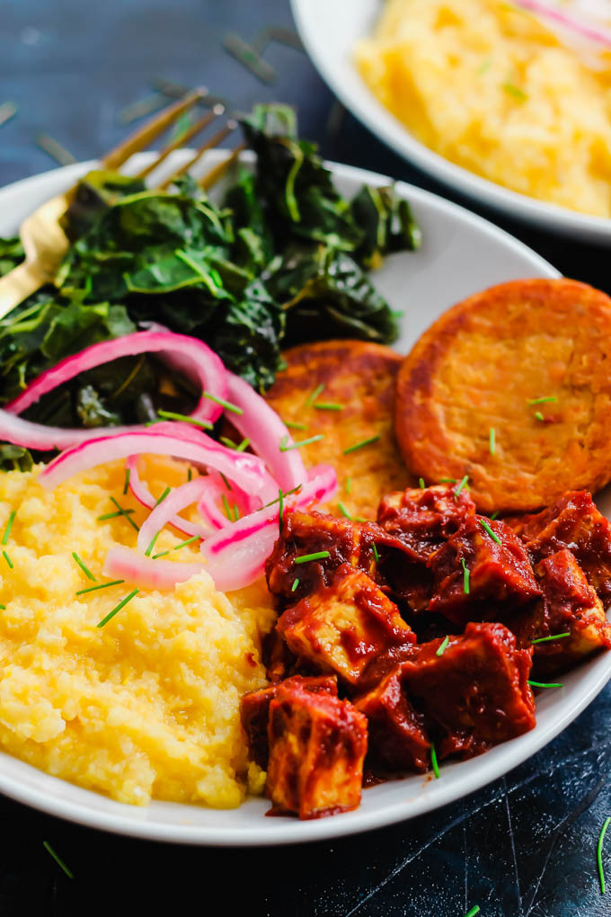 a close up of a bowl of grits, tofu, sweet potatoes and collard greens