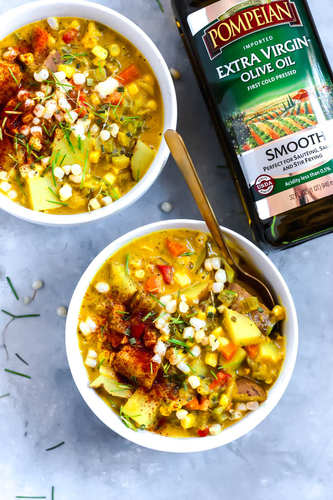 Two bowls of vegan corn chowder next to a bottle of olive oil