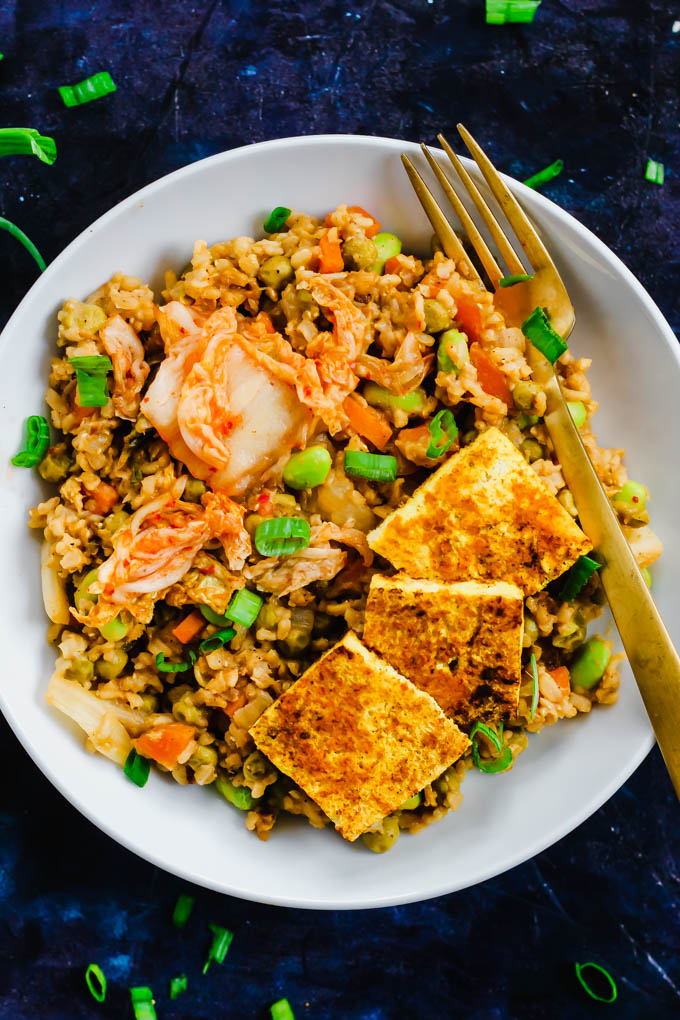 A bowl of kimchi fried rice served with green onions and tofu