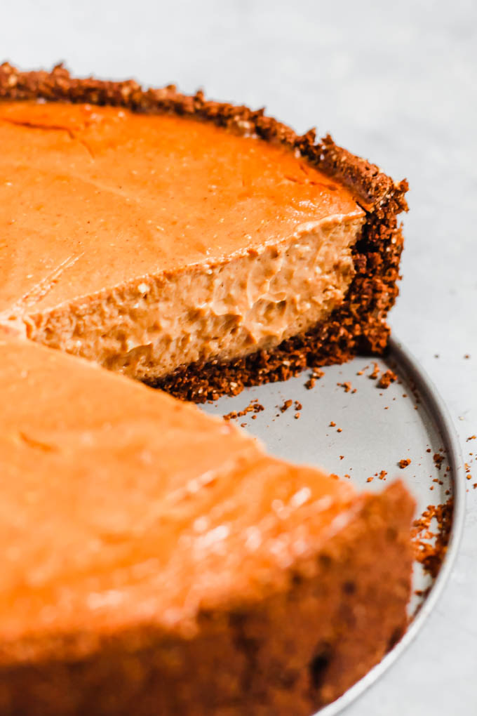a vegan pumpkin cheesecake with a slice cut out