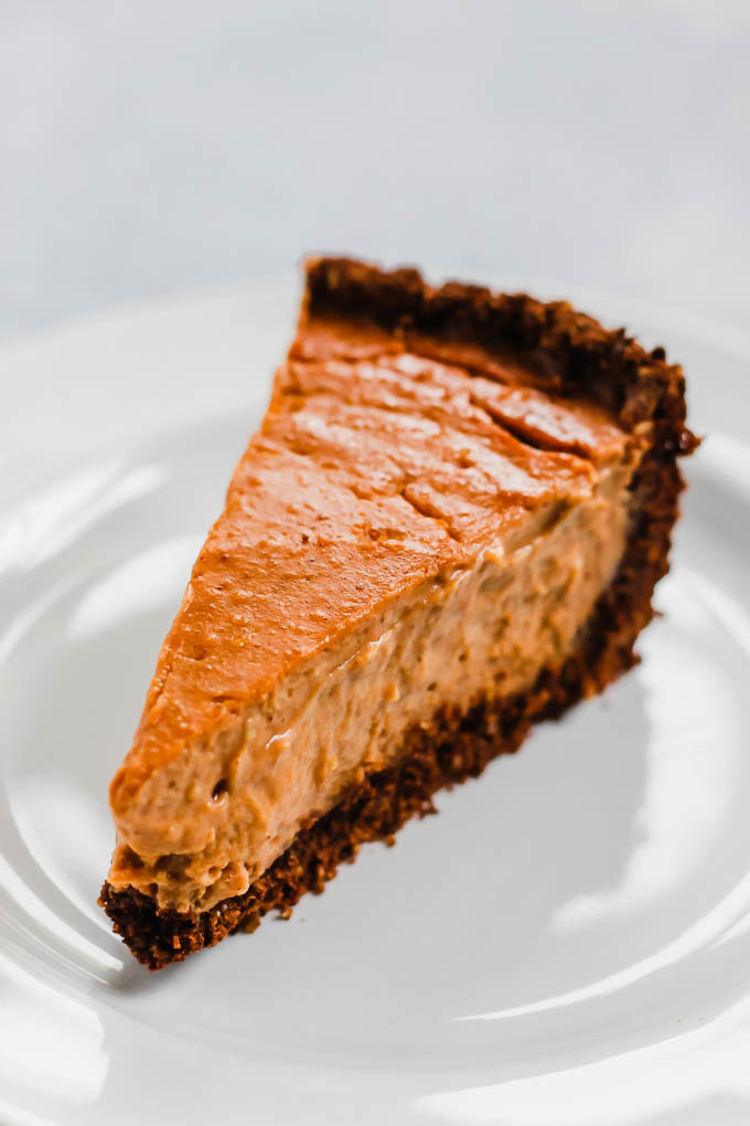 a slice of vegan pumpkin cheesecake with a chocolate crumb crust