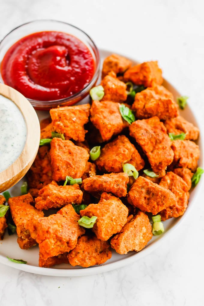 a plate of buffalo tofu nuggets served with ketchup and dairy free ranch