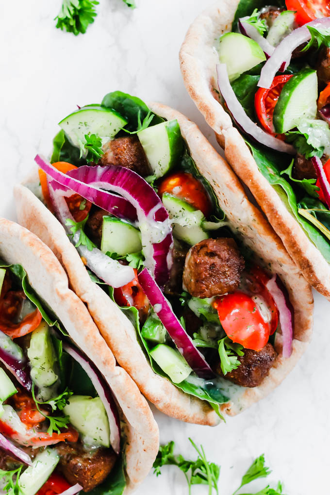 three vegan gyros served with tzatziki and a sprinkle of fresh parsley