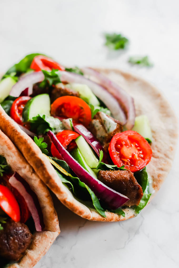 a pita stuffed with vegan beef, fresh vegetables and tzatziki