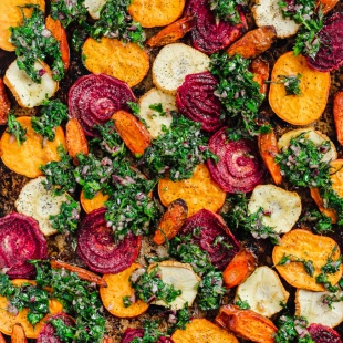 a tray of roasted vegetables with a carrot top chimichurri