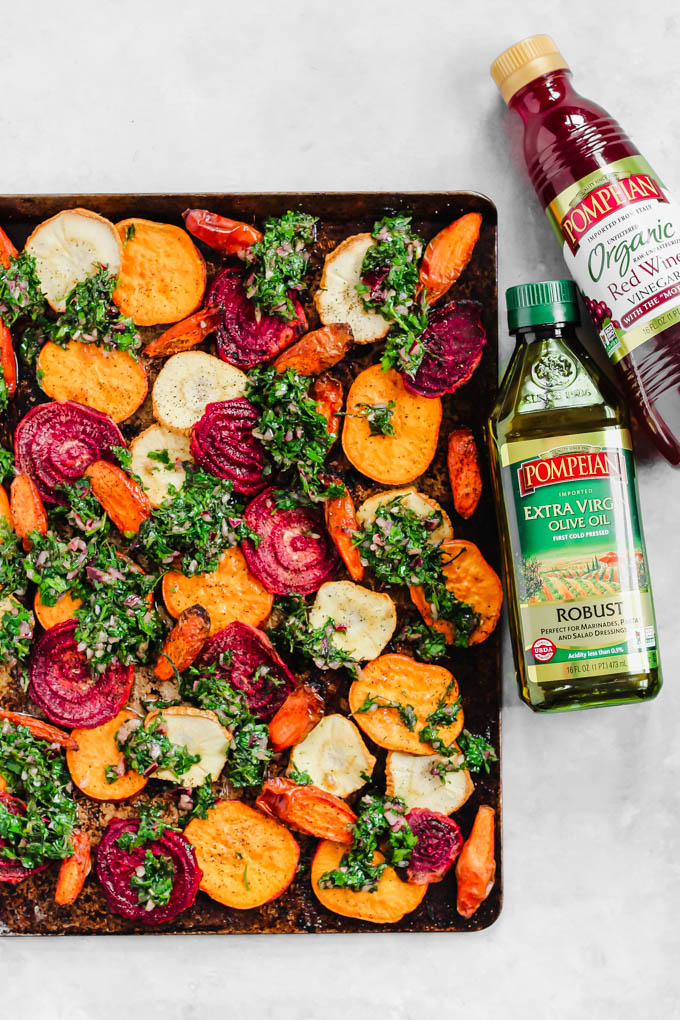 a sheet tray of roasted vegetables next to a bottle of olive oil and a bottle of red wine vinegar