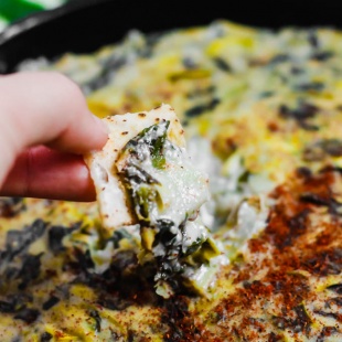 a chip being dipped into spinach dip