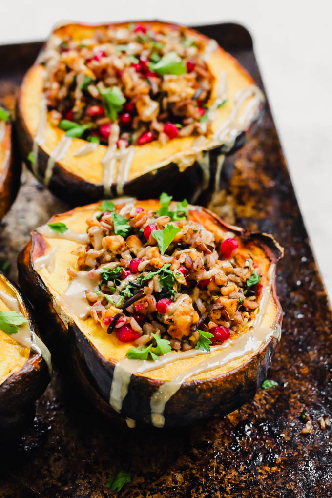 a sheet tray holding two halves of an acorn squash, each filled with tempeh and wild rice