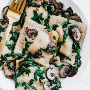 a bowl of vegan mushroom ravioli served with sauteed spinach