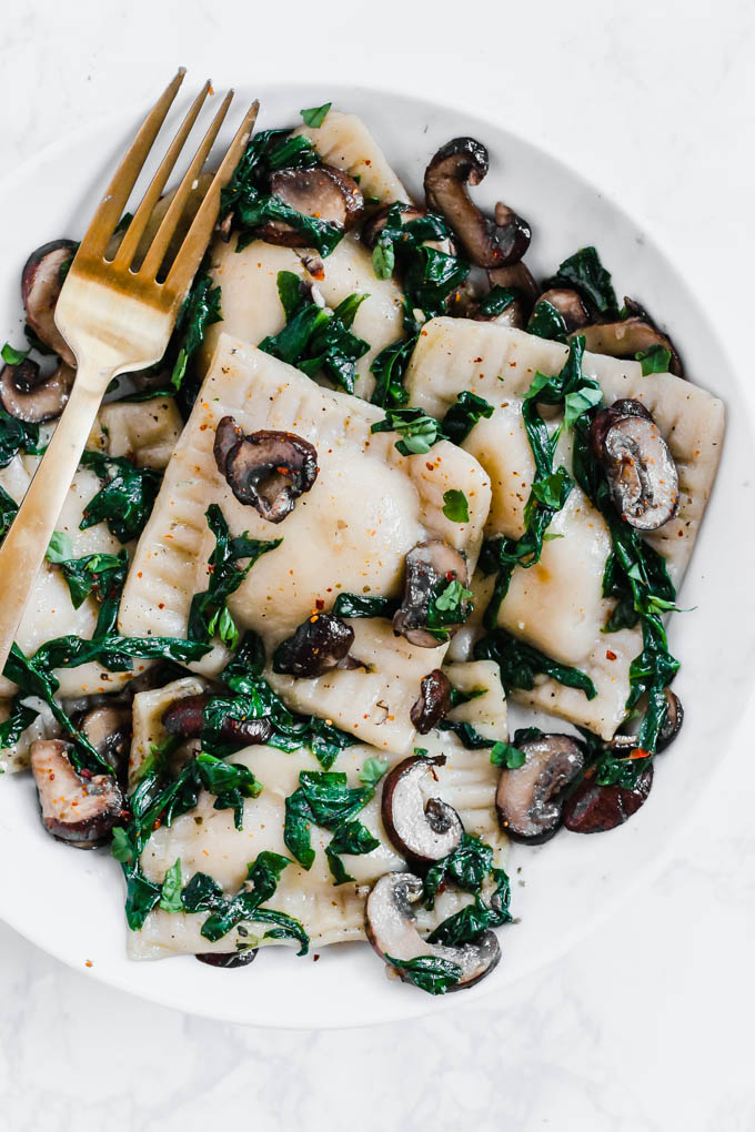 a bowl of vegan mushroom ravioli served with sauteed spinach