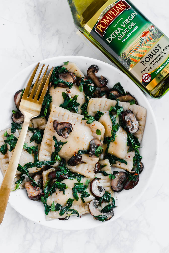 a bowl of mushroom ravioli next to a bottle of olive oil